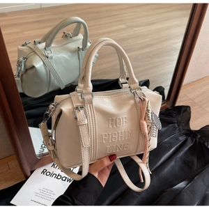Detalle del bolso Boston crema con grabado HOB FISHIN LING y adorno de colgante rosa
