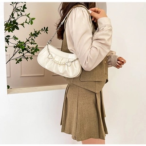 Détail du sac plissé crème avec bandoulière en perles et pendentif coeur en métal argenté