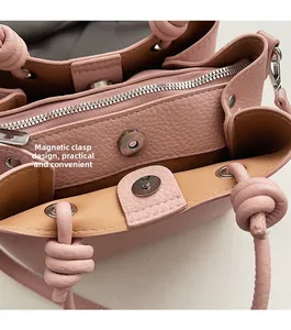 Detail of magnetic snap and zipper closure on pink litchi leather bucket bag