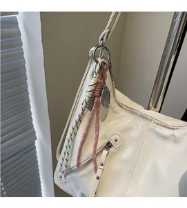 Detail of cream glossy tote bag featuring woven rope charms and silver tennis racket pendant