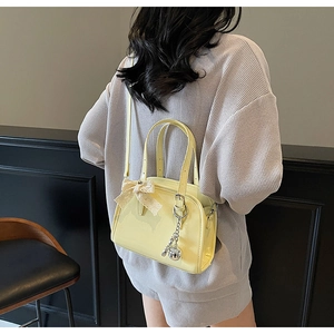 Detail of cream Boston bag featuring beige lace bow and silver spherical pendant charm