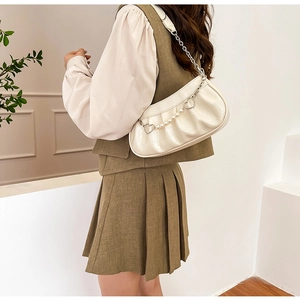 Détail du sac plissé blanc avec chaîne en perles et breloques cœur sur un mannequin