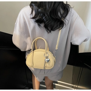 Détail d'un sac bowling en cuir grainé jaune avec pendentif cœur et bandoulière