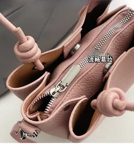Detail of pink lychee texture leather handbag featuring smooth zipper and knotted strap