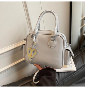 Detail of grey PU leather Boston tote with heart pendant and adjustable shoulder strap