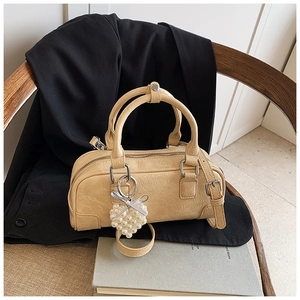 Vue détaillée d'un sac crème avec pendentif cœur en perles posé sur une chaise en bois