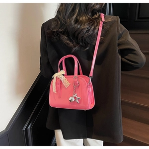 Detail of glossy pink patent leather crossbody bag with lace bow and silver bunny charm