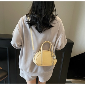 Vue arrière du mannequin portant un mini sac jaune en cuir litchi avec breloque cœur
