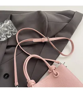 Detail of pink lychee leather bucket bag with knot handle and adjustable strap
