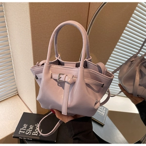 Détail d'un sac à main violet clair brillant avec doubles poignées et boucle en métal