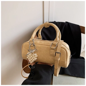 Détail du sac polochon beige avec breloque cœur en perles et nœud argenté