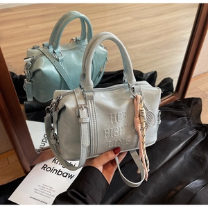 Detalle del bolso bowling azul claro en ecopiel con relieve y colgante de tenis