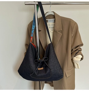 Detail of blue denim hobo bag with ribbon bow and ethnic pattern colorful shoulder strap