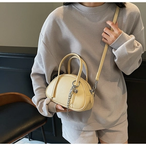 Détail d'un sac à main en cuir grainé crème avec chaîne argentée et pendentif coeur