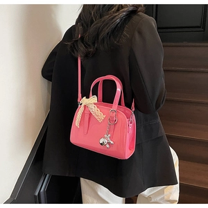 Detail of bright pink patent leather Boston bag with lace bow and silver metal charm