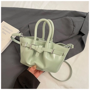Detail of mint green leather bucket bag with top handles and adjustable shoulder strap