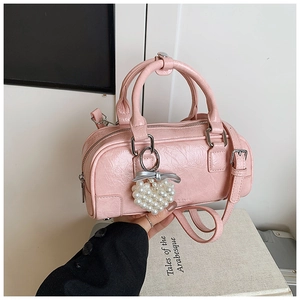Détails d'un sac bowling rose avec texture plissée et breloque cœur en perles décoratif