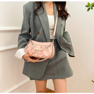 Détail du sac plissé rose avec chaîne de perles et boucle métallique en forme de cœur