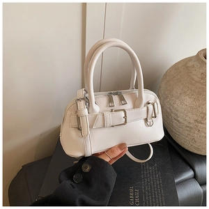 Close-up of white shell-shaped handbag with double zippers and detachable strap
