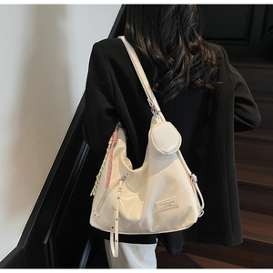 Détail d'un grand sac hobo en cuir verni crème avec petit porte-monnaie rond et charms décoratifs