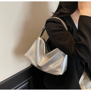 Metallic silver pleated hobo bag shown on model with chic black suit for styling