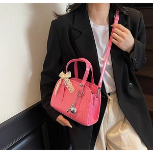 Pink glossy patent leather Boston bag with lace bow and silver pendant detail