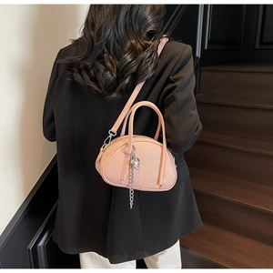 Détail du sac à main rose clair en cuir grainé avec pendentif coeur et bandoulière amovible
