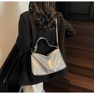 Silver metallic hobo bag detail with sleek handle and detachable strap on a model