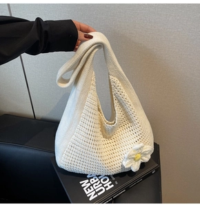 Détail du sac bandoulière en maille avec texture ajourée et accents floraux sur un livre