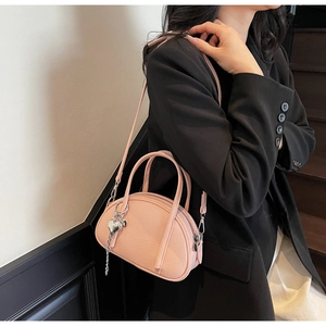 Sac Boston rose à texture lychee avec pendentif cœur argenté sur modèle