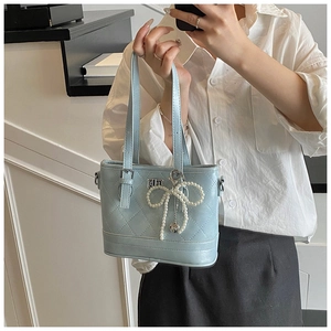 Detail of light blue quilted tote bag with pearl bow charm and metal clasp lock