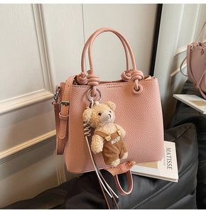 Detailed shot of pink lychee leather bucket bag with cute bear charm and knotted handle