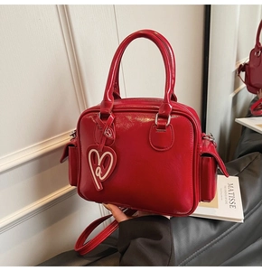 Detail of red patent leather Boston tote bag showing double handles and heart-shaped charm