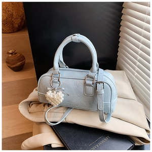 Détail du sac bowling en cuir bleu clair avec breloque cœur en perles et sangle