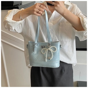 Close-up of light blue quilted tote with diamond stitching and pearl bow charm detail