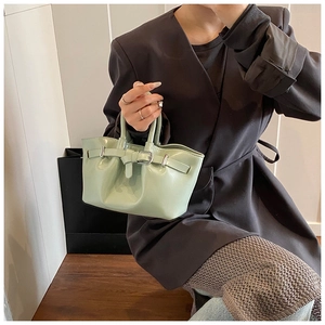 Detail of mint green glossy patent leather handbag with decorative silver buckle