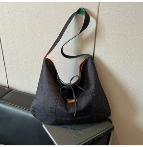 Detail of a large denim tote bag featuring a bow tie and inner lining on a leather sofa