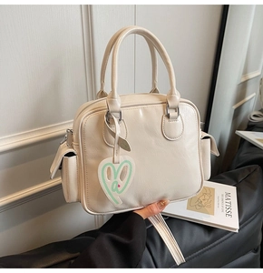 Detailed shot of cream Boston tote bag with silver hardware and heart charm
