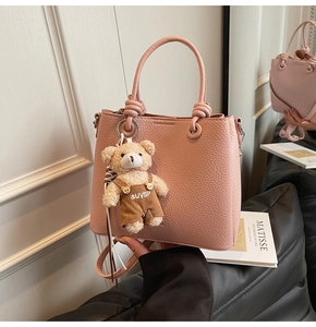 Detail of pink lychee leather bucket bag with silver hardware and cute bear charm