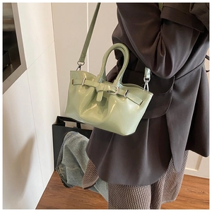 Detail of light green patent leather bucket bag with glossy finish and metal buckle