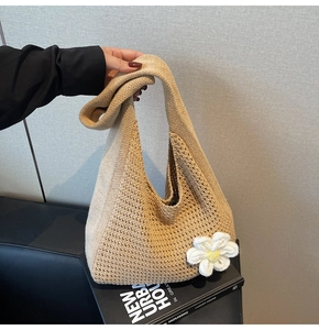 Détail d'un sac cabas en tricot beige ajouré avec fleur au crochet et accessoire livre