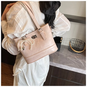 Detail of pink quilted leather shoulder bag with pearl bow charm and metal twist lock