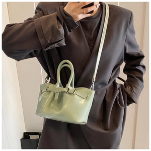 Close-up of mint green patent leather bucket bag with decorative buckle and slim strap