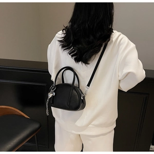 Détail d'un sac à main noir en cuir grainé avec grand pendentif en forme de cœur argenté