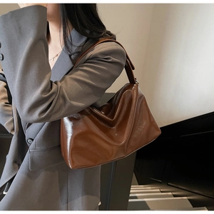 Detailed texture of glossy vintage brown leather underarm bag with metal zipper