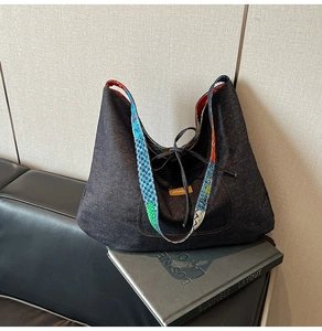 Detail of large denim tote bag featuring a colorful geometric strap and drawstring closure