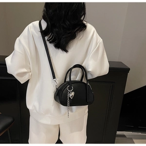 Détail du sac bandoulière noir en cuir grainé avec pendentif cœur argenté sur modèle