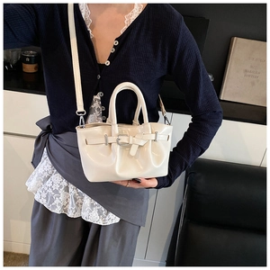 Detail of cream pleated bucket bag with silver hardware and detachable crossbody strap