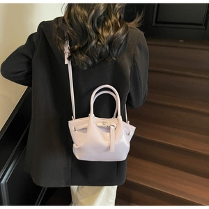 Détail du sac seau lavande porté en bandoulière par un mannequin en blazer noir