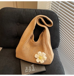 Gros plan sur un sac cabas en tricot kaki avec une breloque marguerite blanche